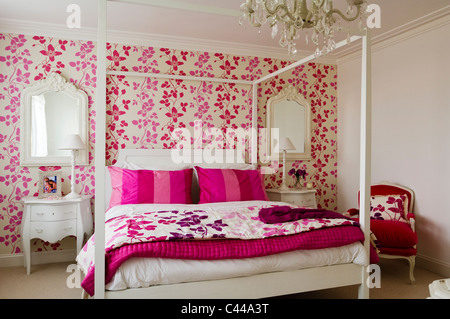 Weiße Schlafzimmereinrichtungen Bett im Schlafzimmer mit Designers Guild Pink floral gemusterte Tapeten und Kronleuchter Stockfoto