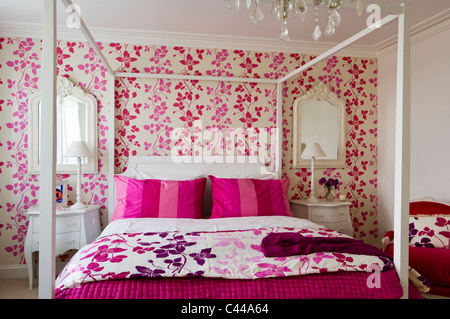 Weiße Schlafzimmereinrichtungen Bett im Schlafzimmer mit Designers Guild Pink floral gemusterte Tapeten und Kronleuchter Stockfoto