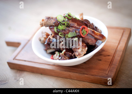 Ein Gourmet-Gericht aus klebrigen chinesischen Stil spare-Ribs serviert mit Chili, Ingwer und Frühlingszwiebeln Stockfoto