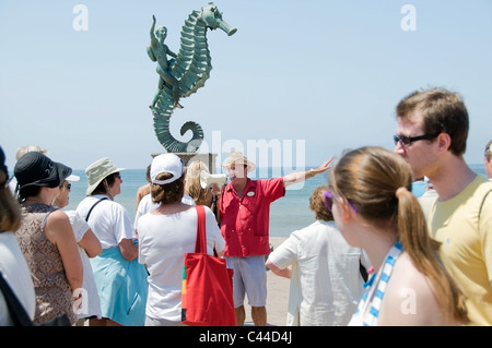 Eine Tourguide befasst sich eine Menge von Touristen vor "The Sea Horse" Skulptur auf dem Malecon in Puerto Vallarta, Mexiko. Stockfoto