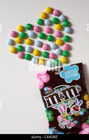 Limited Edition choco M&M's mit Inhalt in Form eines Herzens auf weißem Hintergrund angeordnet Stockfoto