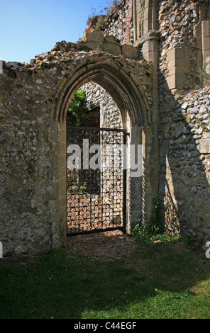 Eine alte gewölbte Tür mit einem modernen schmiedeeisernen Tor in einer Ecke der Ruinen von Norden Creake Abbey, Norfolk, England, UK. Stockfoto