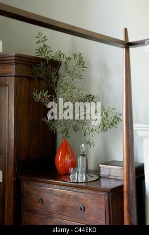 Olivenzweig im Retro-Stil orange Vase auf antikem Holz Kommode Stockfoto