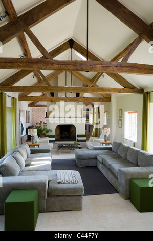 Öffnen Sie Plan umgebaute Scheune mit Holzbalken an den Decken, graue Sofas und offenem Kamin Stockfoto