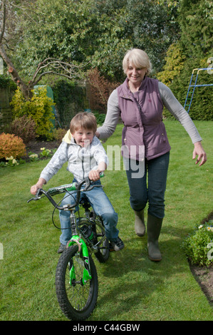 Großmutter Enkel, mit dem Fahrrad in einem Garten hinter dem Haus Unterricht Stockfoto