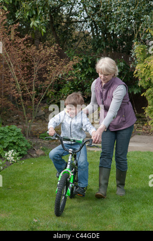 Großmutter Enkel, mit dem Fahrrad in einem Garten hinter dem Haus Unterricht Stockfoto