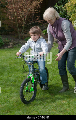 Großmutter Enkel, mit dem Fahrrad in einem Garten hinter dem Haus Unterricht Stockfoto