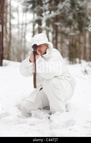 Soldat in weiße Tarnung mit Scharfschützengewehr im Winterwald. Stockfoto