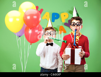 Porträt von intelligenten jungen in lustige Brillen hineinblasen kindisch Spielzeug Stockfoto