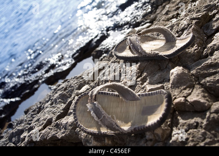 Vorbei schwimmen - Flipflops an einem steinigen Strand. Stockfoto