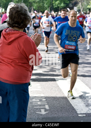 Einen mittleren Alters weibliche Zuschauer applaudieren 10km Rennen Konkurrenten Läufer mit Fokus auf Händen London England Europa Stockfoto