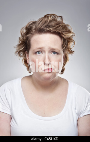 Ein Studio-Porträt einer schrulligen übergewichtigen jungen Frau haben einen schlechten Tag. Sie hat einen niedergeschlagenen aber humorvollen Ausdruck. Stockfoto