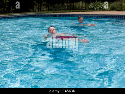 Baby-Boomer paar schwebend in einem Hinterhof-Pool an einem heißen Sommertag Stockfoto