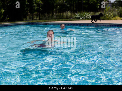 Baby-Boomer paar schwebend in einem Hinterhof-Pool an einem heißen Sommertag Stockfoto