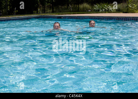 Baby-Boomer paar schwebend in einem Hinterhof-Pool an einem heißen Sommertag Stockfoto