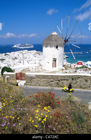 Mann fährt Motorroller vorbei Windmühle auf der Insel Mykonos in Griechenland. Stockfoto