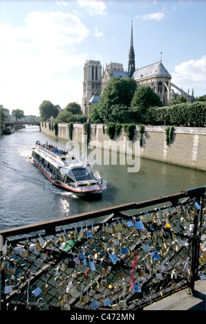 Blick von der Brücke verziert mit Liebhaber Schlösser und Ausflugsboot auf Seine Segeln vorbei an Notre Dame Kathedrale Stockfoto