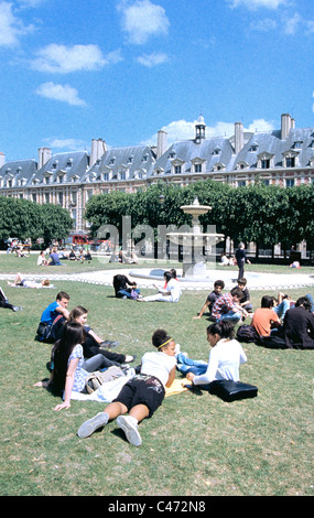 Studenten und andere junge Leute sitzen und liegen auf dem Rasen im Park in Louis 1V Platz in Paris Stockfoto