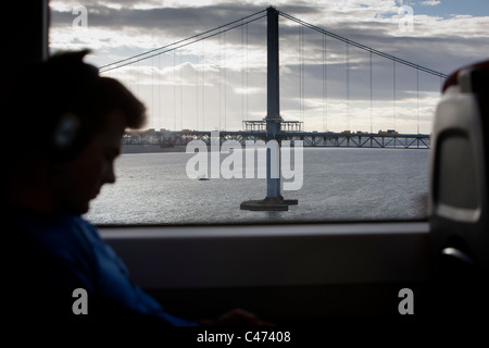 Blick auf die Forth Road Bridge von Personenzug über Forth Rail Bridge mit Beifahrer im Silhouette, Edinburgh, Schottland Stockfoto