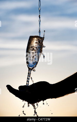 Wasser wird in ein Champagnerglas gegossen. Silhouette Stockfoto