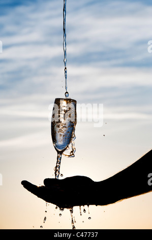 Wasser wird in ein Champagnerglas gegossen. Silhouette Stockfoto