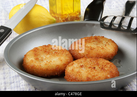drei frisch gebratenen Fisch Kuchen in einer Pfanne Stockfoto