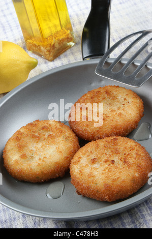drei frisch gebratenen Fisch Kuchen in einer Pfanne Stockfoto