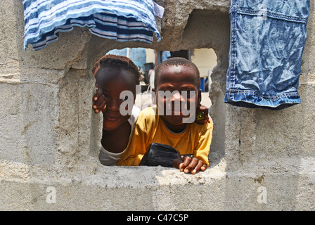 Kinder spähen durch Loch in einer Wand in Abidjan, Elfenbeinküste, Westafrika Stockfoto