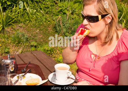 Eine Frau in ihren Dreißigern hat Tee und einen Scone im Vereinigten Königreich Stockfoto