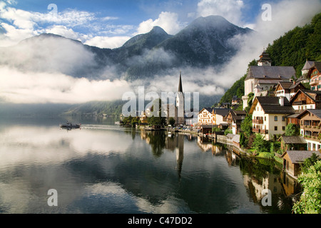 Die Morgensonne weckt Hallstatt, Österreich als ein Wassertaxi beginnt über den Hallstätter sehen. Stockfoto