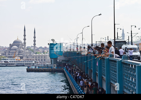 Fischer und Stangen auf Galata-Brücke, Istanbul. Neue Moschee (Yeni Cami) ist im Hintergrund Stockfoto