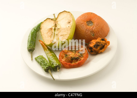 Alten faulen Apfel, Chilis und Tomaten auf einem Teller. Sie hatten im Kühlschrank für etwa einen Monat bis zum Zerfall gelassen worden. Stockfoto