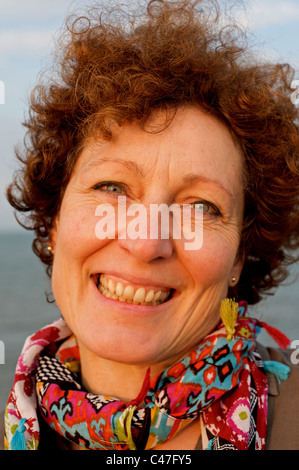 Lächelnde Frau mittleren Alters mit dem lockigen Haar Stockfoto