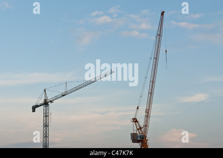 Zwei große Kräne stehen vor einem blauen Himmel mit Wolken am Abend. Stockfoto