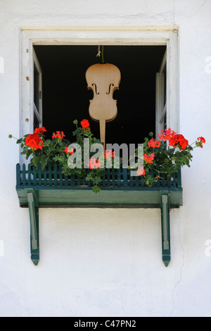 Violine Musikinstrument hängt in einem geöffneten Fenster in Stadt Mittenwald in Oberbayern, Deutschland Stockfoto