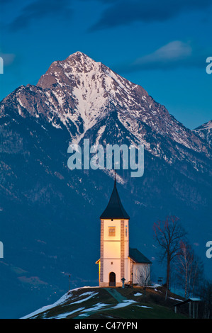 Die Kirche des Heiligen Primus und Felician bei Jamnik, Slowenien, mit der Steiner Alpen im Hintergrund. Stockfoto
