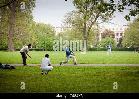 Junge Männer spielen Cricket auf einem Wanderweg im Regents Park, London. Stockfoto