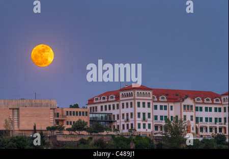 Vollmond steigt über alte Häuser am Cemetario Maior, Portugal Stockfoto