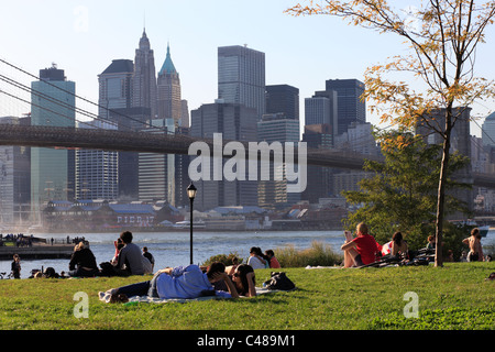 Menschen liegen auf dem Rasen unter der Brooklyn Bridge, New York City, USA Stockfoto