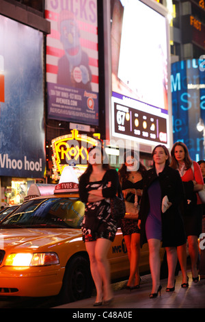 Vier junge Frauen auf dem Times Square, New York City, USA Stockfoto