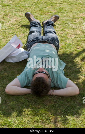 Mann liegt auf dem Rasen dösen im Schatten des Baumes auf der Hay Festival 2011 Stockfoto