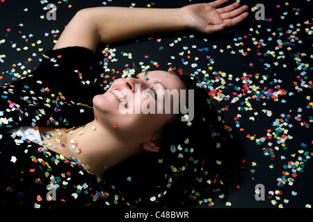 Eine lachende Frau liegt im Konfetti Stockfoto