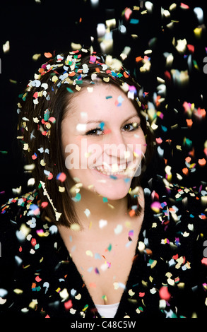 Eine Frau lächelt in einem Regen von Konfetti Stockfoto