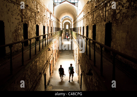 Touristen gehen Sie einer bröckelnden Zellblock am Eastern State Penitentiary in Philadelphia, PA. Das Gefängnis soll verfolgt werden. Stockfoto