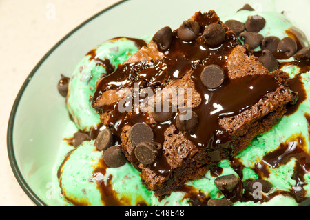 Ein Schokoladen-Brownie mit Schokoladenstückchen und Sirup auf Mint Chocolate Ice Cream gekrönt. Stockfoto