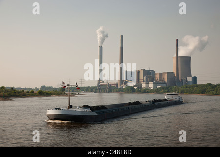 Ein Kohle-Lastkahn Produkt bewegt sich auf den Rhein River, Deutschland, vor einem Kernkraftwerk. Stockfoto