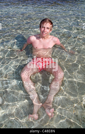 Modell veröffentlicht Mann im Sommerurlaub entspannen und im Meer am Strand liegend Stockfoto