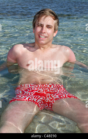 Modell veröffentlicht Mann im Sommerurlaub entspannen und im Meer am Strand liegend Stockfoto