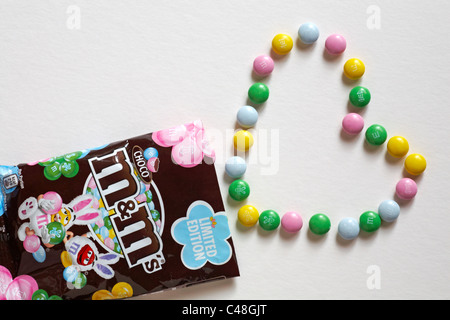 Choco limited edition M&Ms mit Inhalt in Herzform auf weißem Hintergrund angeordnet Stockfoto