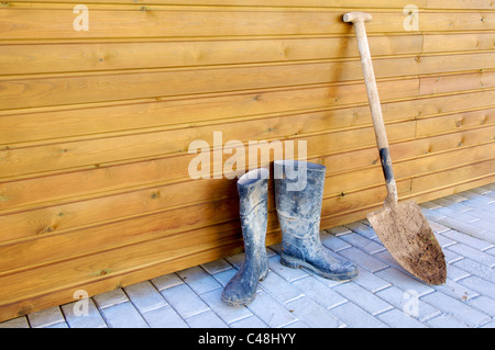 Schaufel und Gummistiefel, basierend auf einer Holzwand Stockfoto